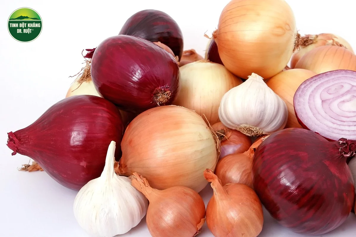 Củ hành tây, hành tím và tỏi tươi xếp chồng trên nền trắng, một củ hành tím cắt đôi lộ lớp vòng